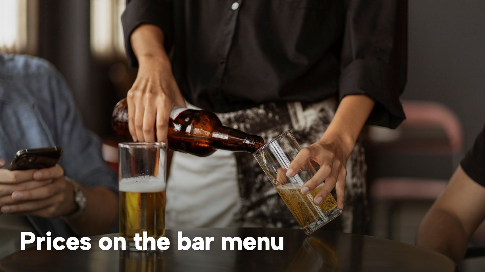 A bartender pouring beer from a bottle into a glass at a bar counter. The image carries the words "Prices on the bar menu".