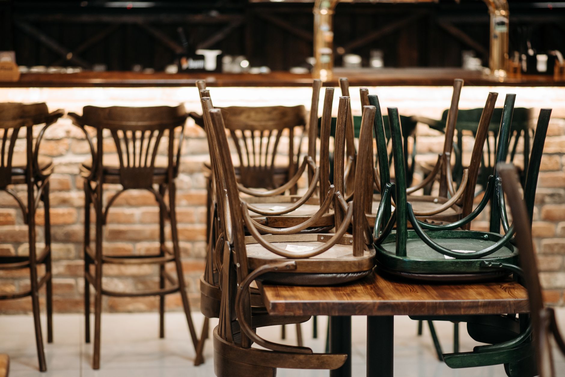 Wooden chairs stacked upside down on tables in an empty restaurant before opening.