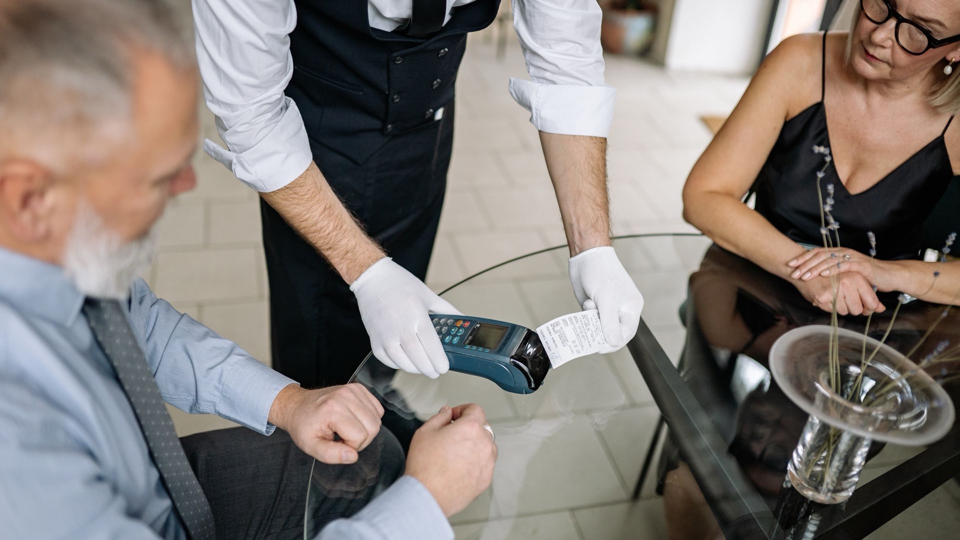 A couple making a contactless payment using a credit card at a restaurant table.