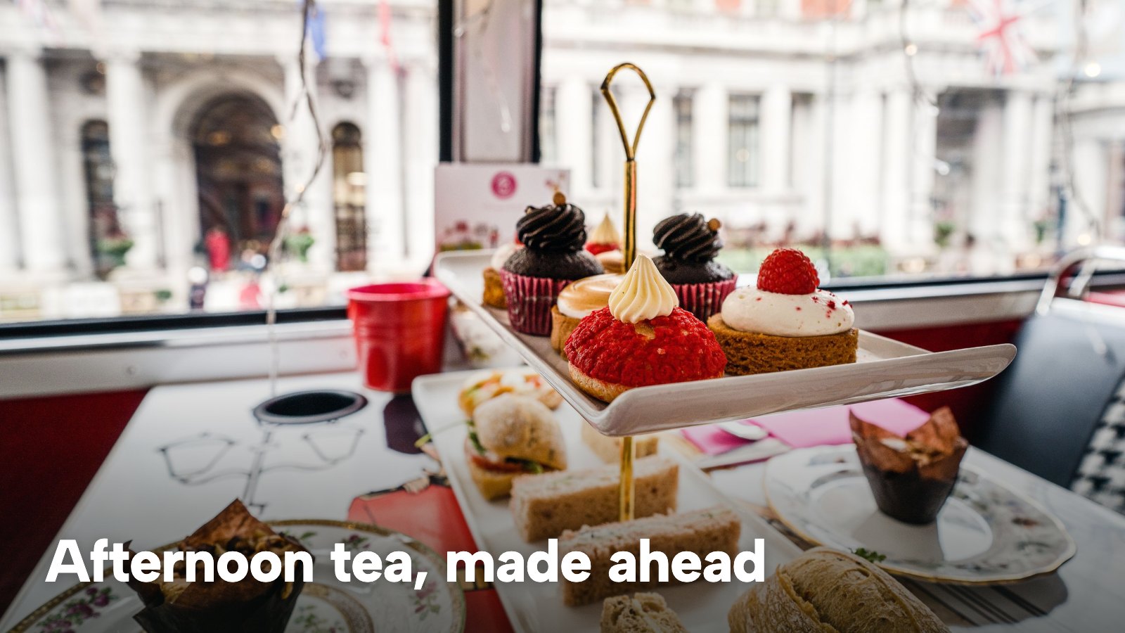An afternoon tea set with sandwiches, scones and cakes on a stand by a window. The image carries the words "Afternoon tea, made ahead".