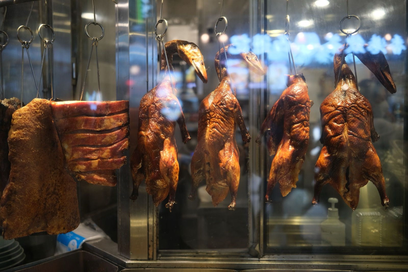 Roast ducks hanging in a restaurant kitchen window.