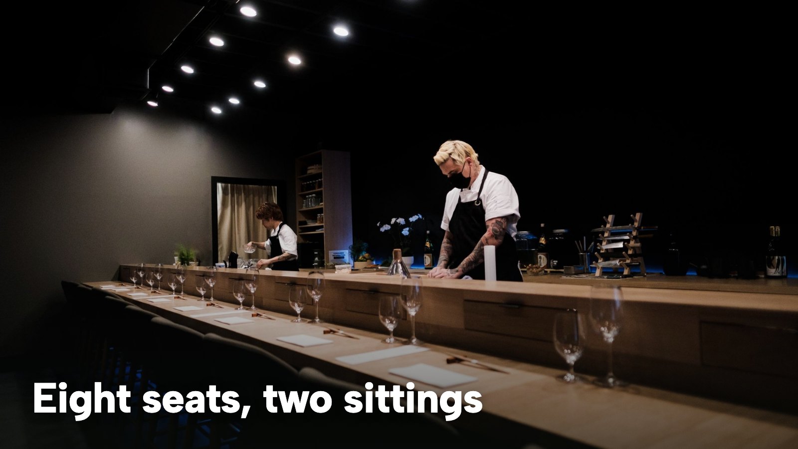 Chefs preparing sushi at a dimly lit omakase counter. The image carries the words "Eight seats, two sittings".