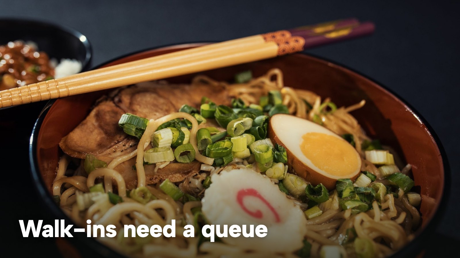 A bowl of ramen with a boiled egg, scallions and chopsticks. The image carries the words "Walk-ins need a queue".