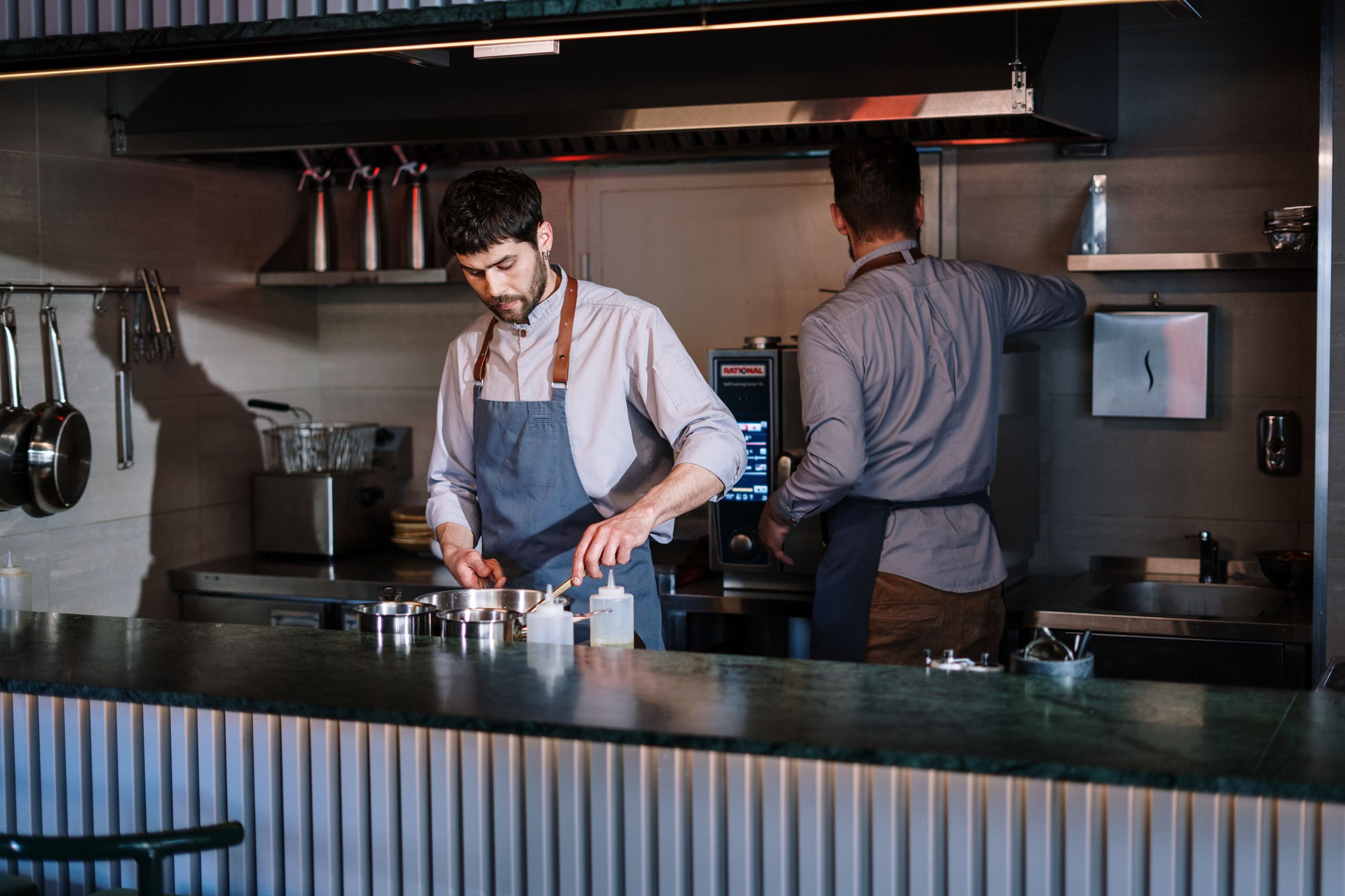 Two chefs working at an open kitchen counter.