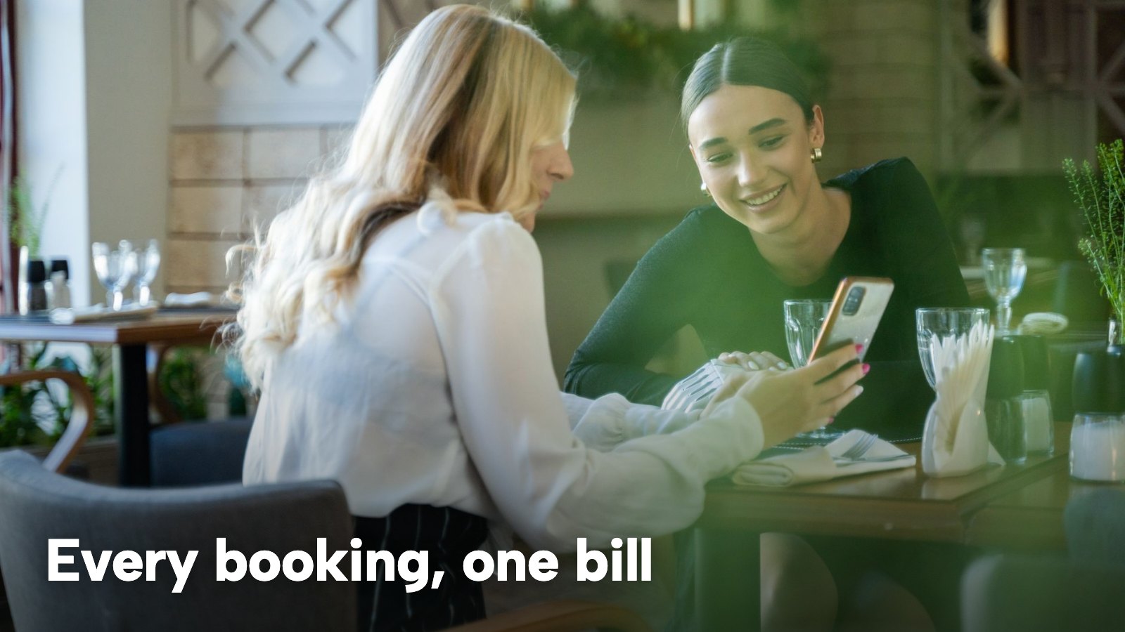 Two guests at a restaurant table looking at a phone together. The image carries the words "Every booking, one bill".