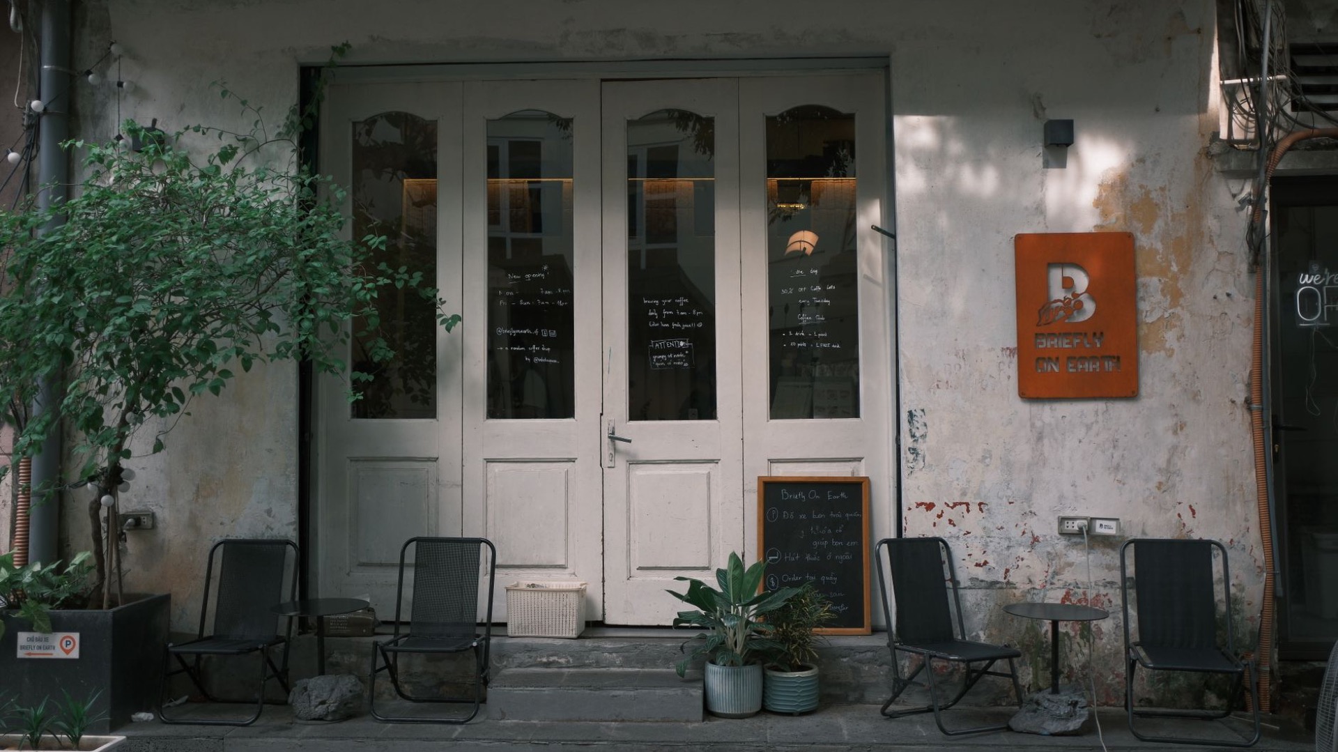 A quiet restaurant entrance with tall glazed doors and chairs set out on the terrace.