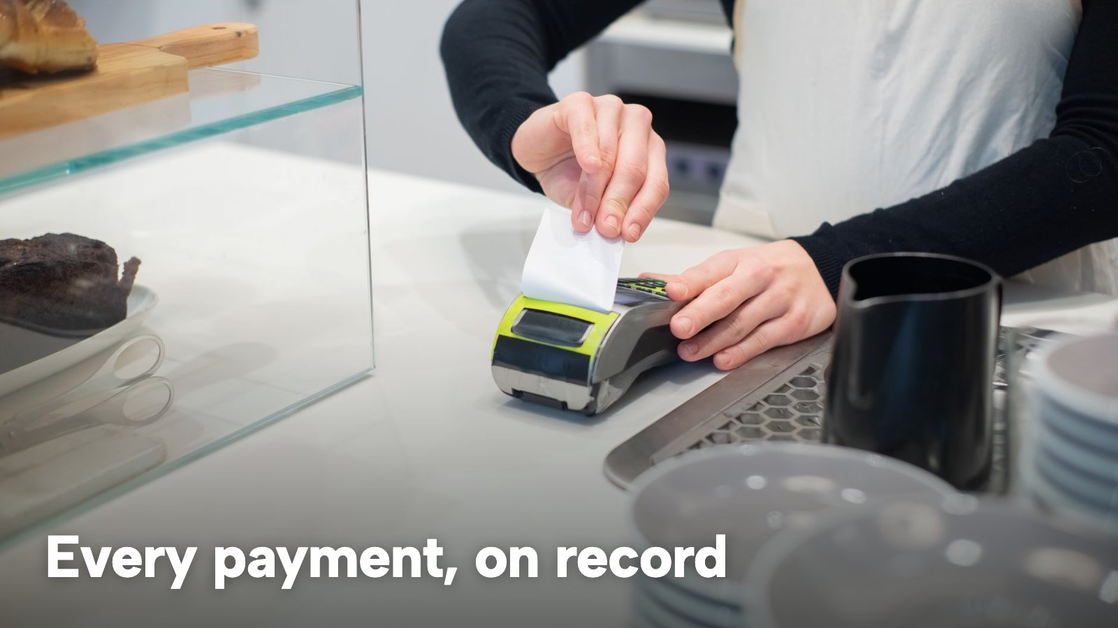 A card reader at a café counter printing a receipt as the payment goes through. The image carries the words "Every payment, on record".