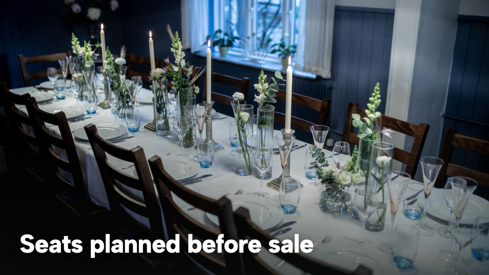 A long dining table laid with candles and glasses before an evening event. The image carries the words "Seats planned before sale".