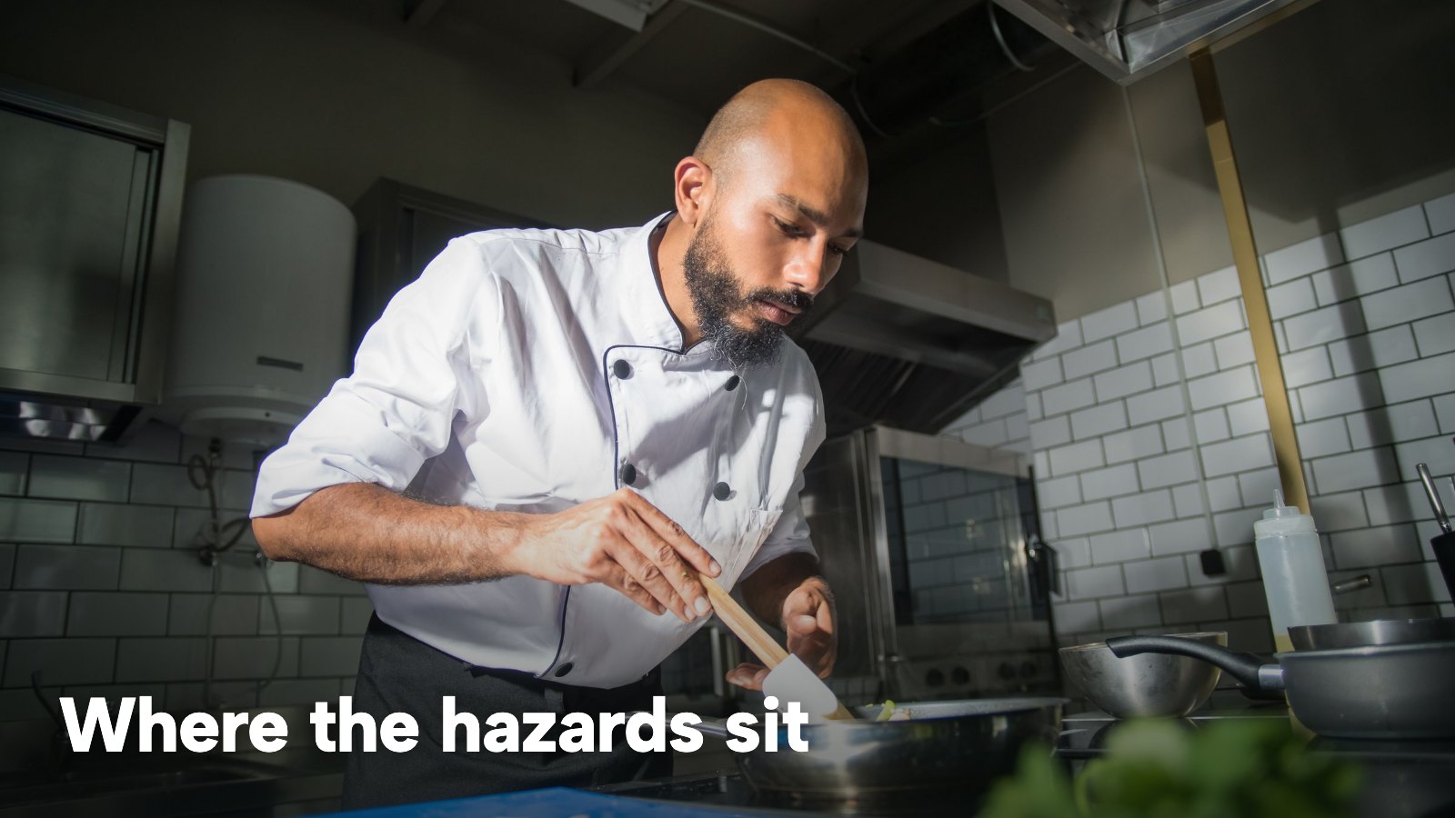 A chef cooking at the stove in a commercial kitchen. The image carries the words "Where the hazards sit".