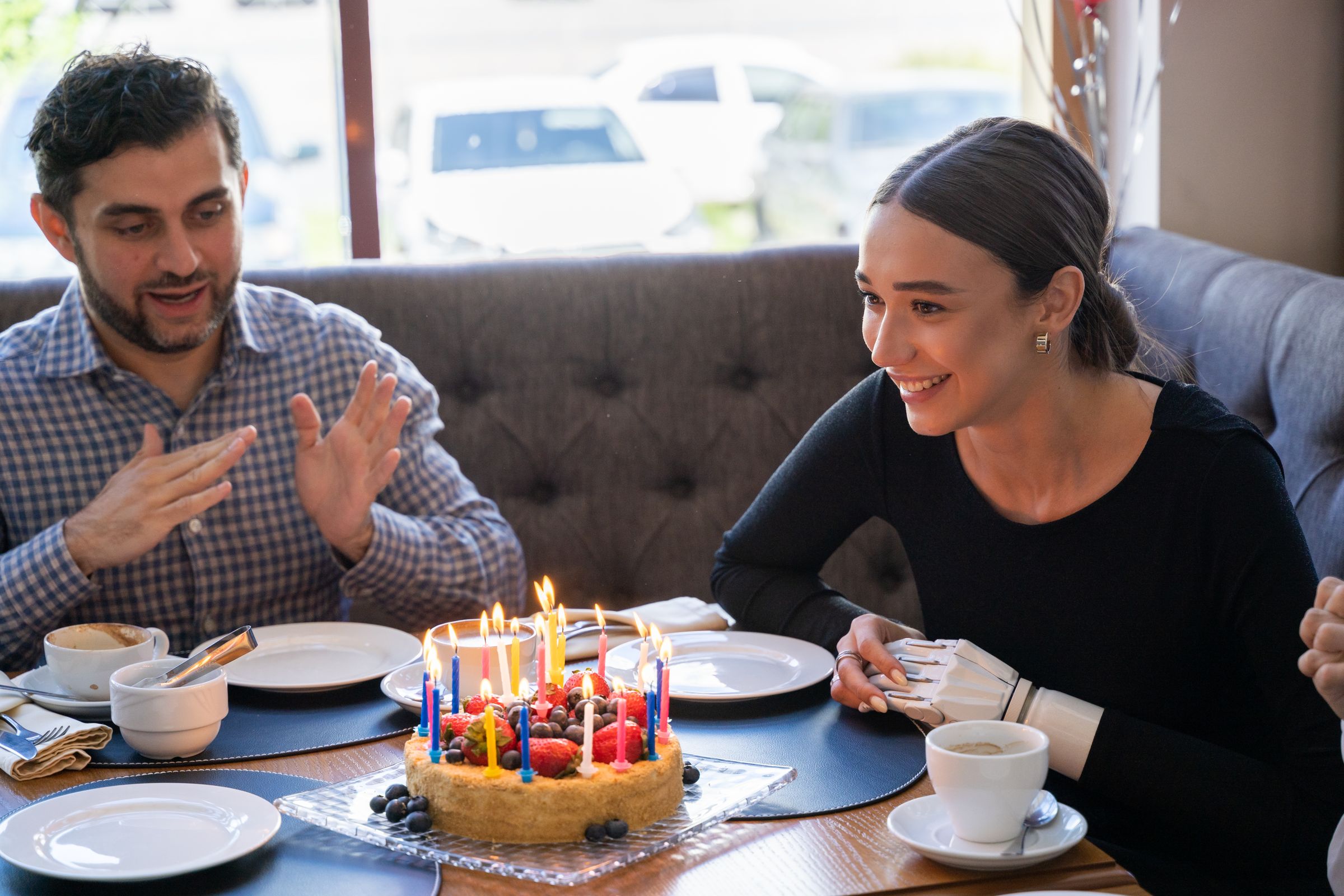 Friends celebrating a birthday at a restaurant table with a cake.