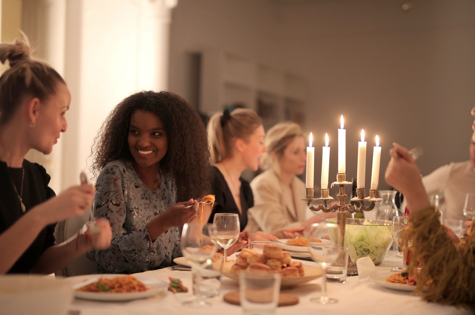 Friends laughing over dinner at a candle-lit table.