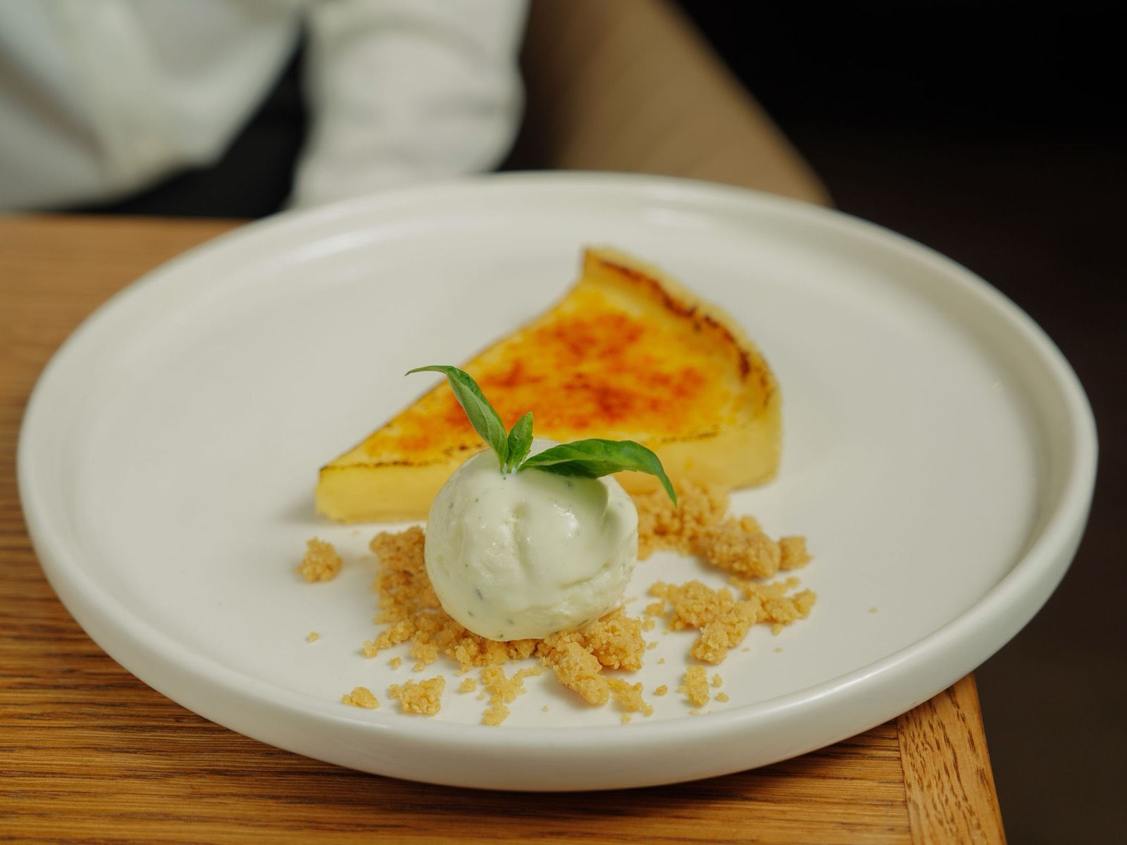 A plated dessert with a slice of tart and cream.