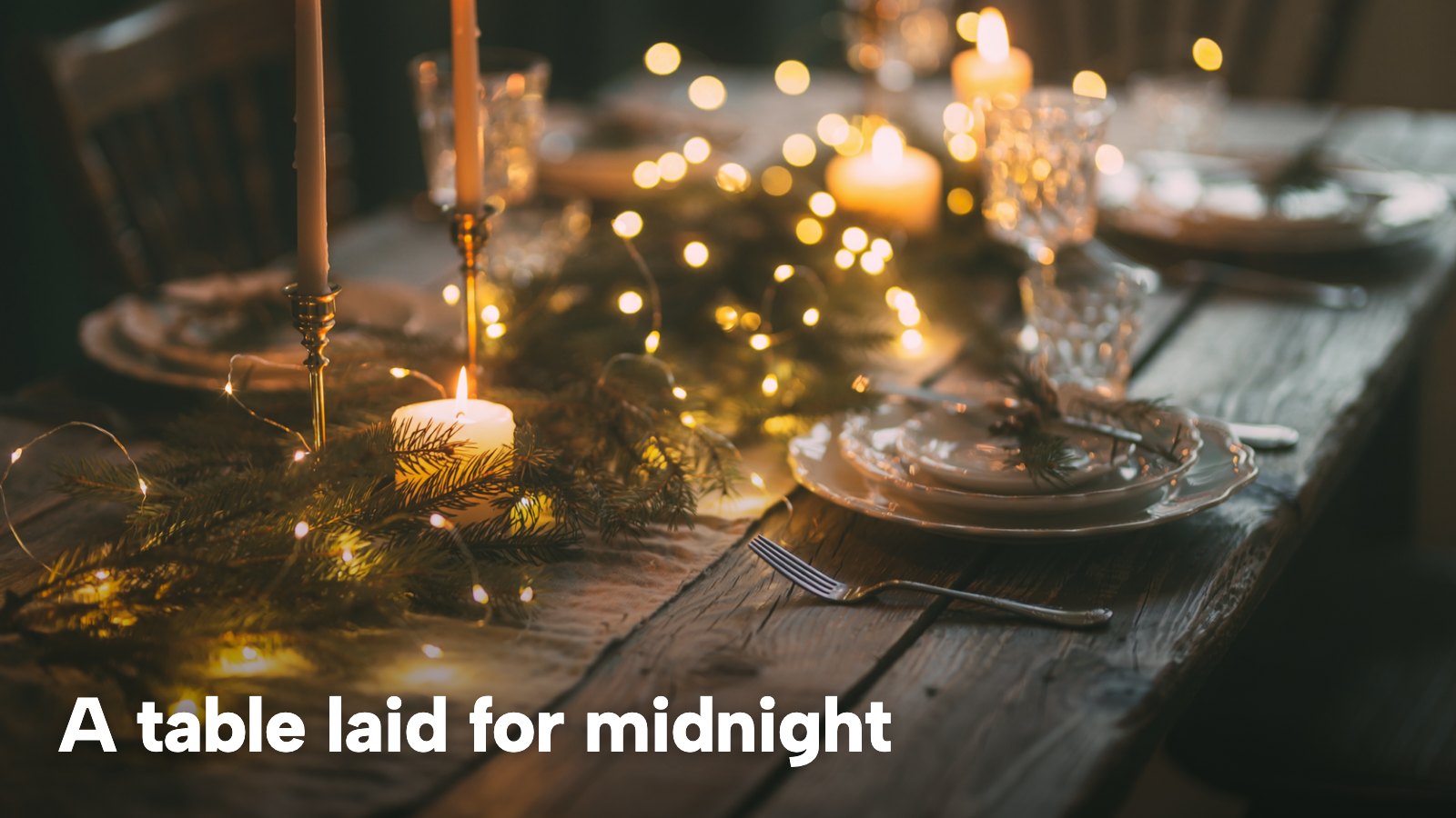 A dinner table set with candles and fairy lights for a celebration. The image carries the words "A table laid for midnight".