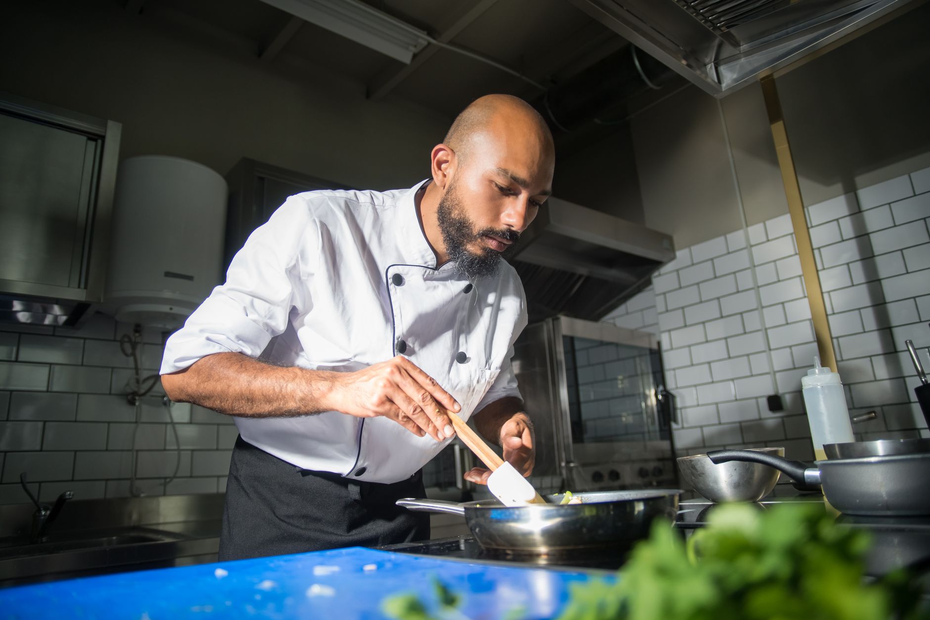 A chef plates a dish in a modern restaurant kitchen.