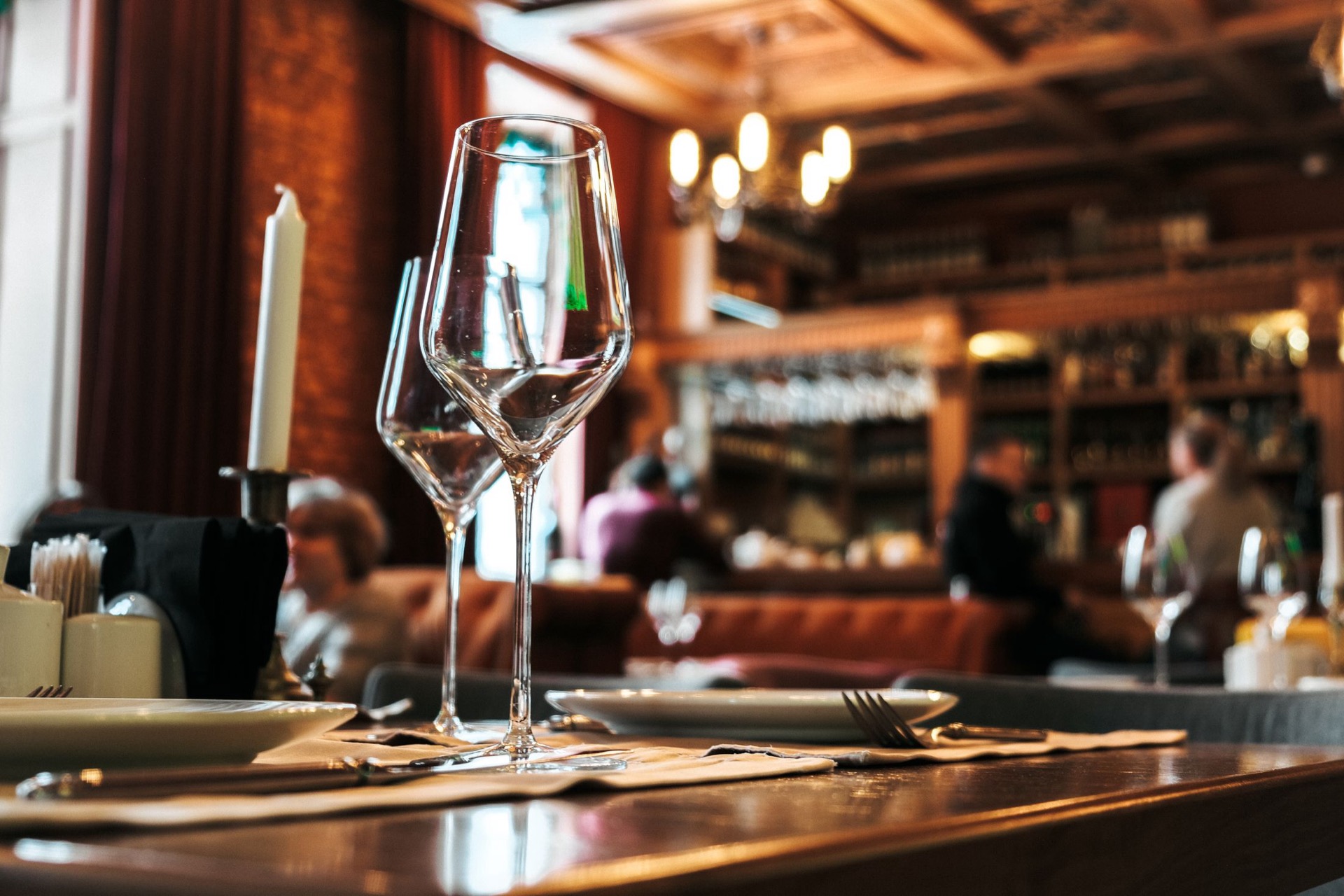 Wine glasses on a bar counter in a warmly lit restaurant.